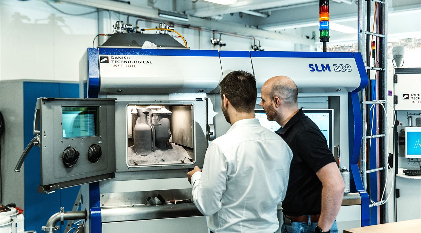 To mænd stående foran åben 3D-printer